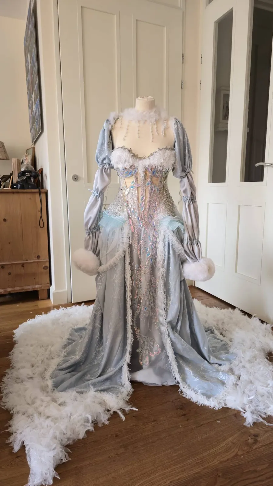 Hellblaues Winterfeen-Kleid mit Federschleppe, Puffärmeln und schimmernder Paillettenstickerei auf einer Schneiderpuppe